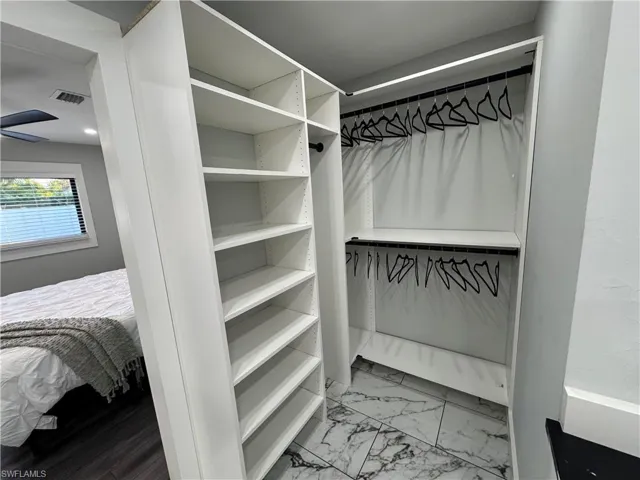 Walk in closet featuring light marble finish floors