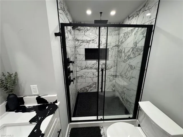 Bathroom featuring vanity and a marble finish shower