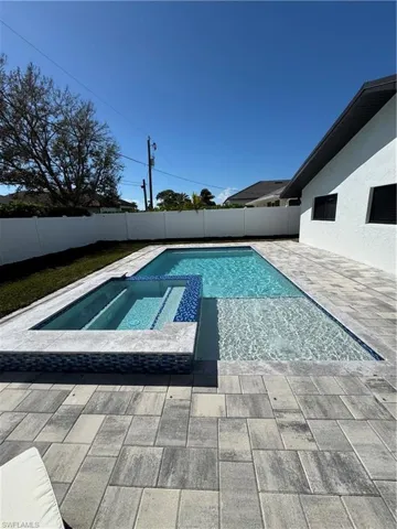 Integrated pool / spa with a fenced backyard and a patio