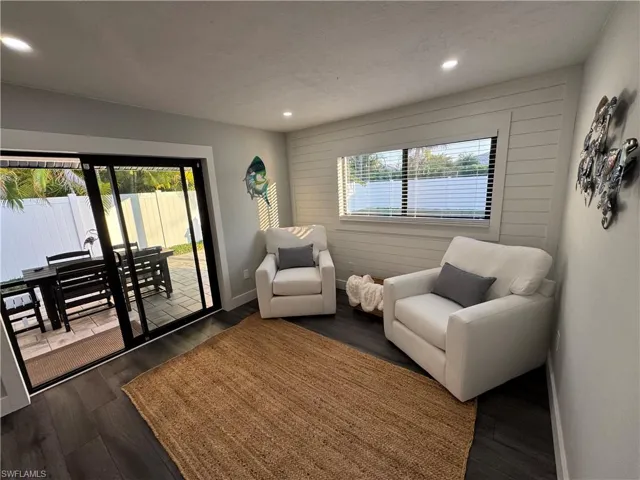 Living area featuring dark wood-style flooring, recessed lighting, and wood walls