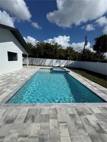 Combined pool / hot tub featuring a fenced backyard and a patio area