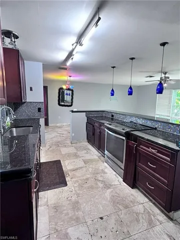 Kitchen featuring sink, hanging light fixtures, backsplash, stainless steel electric range oven, and ceiling fan