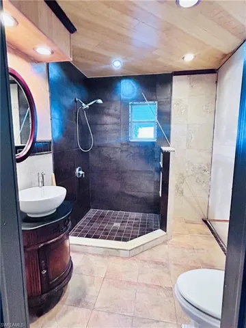 Bathroom featuring tile patterned floors, wood ceiling, vanity, and a tile shower