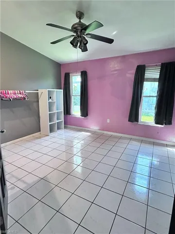Tiled empty room with ceiling fan and a healthy amount of sunlight