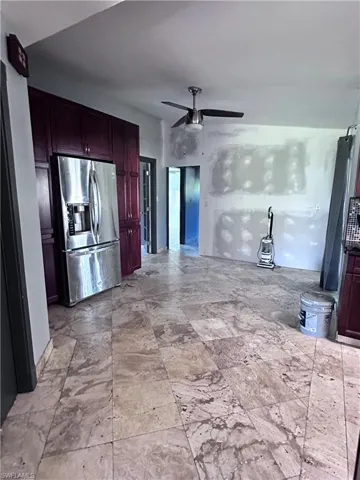 Kitchen with ceiling fan, light tile patterned floors, and stainless steel refrigerator with ice dispenser
