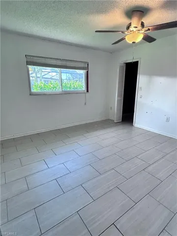 Spare room with a textured ceiling, ceiling fan, and light tile patterned floors
