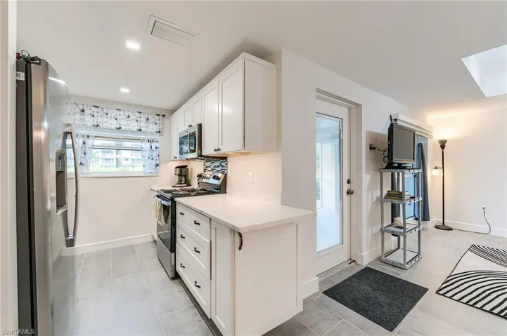 Kitchen featuring white cabinetry, light countertops, stainless steel appliances, and a mosaic tile backsplash