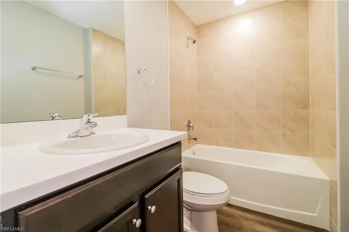 Bathroom featuring vanity, tub / shower combination, and dark wood-style flooring