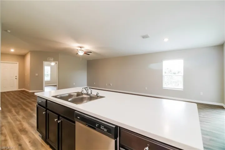Kitchen featuring light countertops, dark wood-type flooring, dishwasher, open floor plan, and recessed lighting