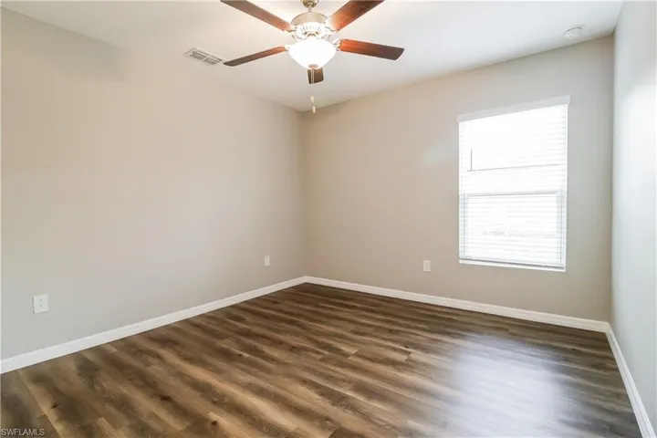 Unfurnished room featuring dark wood-style flooring and ceiling fan