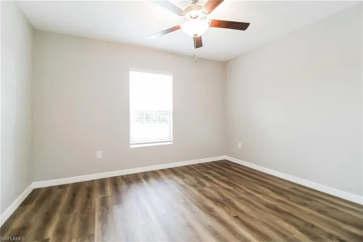 Unfurnished room with dark wood-type flooring and a ceiling fan
