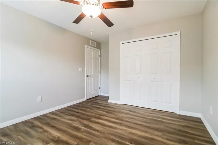 Unfurnished bedroom with dark wood finished floors, ceiling fan, and a closet