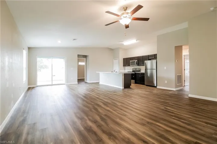 Unfurnished living room featuring lofted ceiling, ceiling fan, and dark wood-type flooring