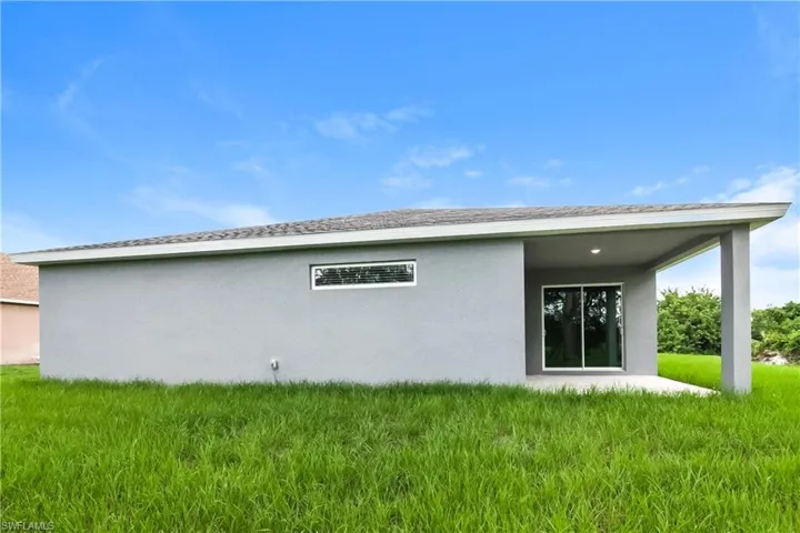 Back of property with a patio area, stucco siding, and a yard