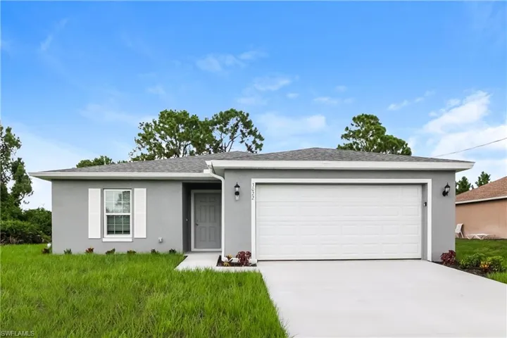Ranch-style house featuring a garage, driveway, stucco siding, a front yard, and a shingled roof