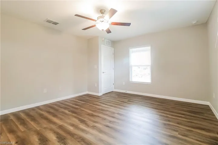 Spare room with dark wood-style flooring and a ceiling fan