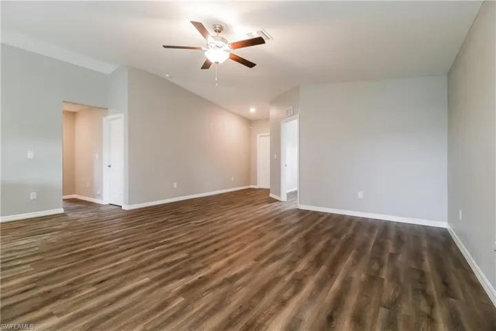 Spare room featuring a ceiling fan, dark wood-style floors, and vaulted ceiling