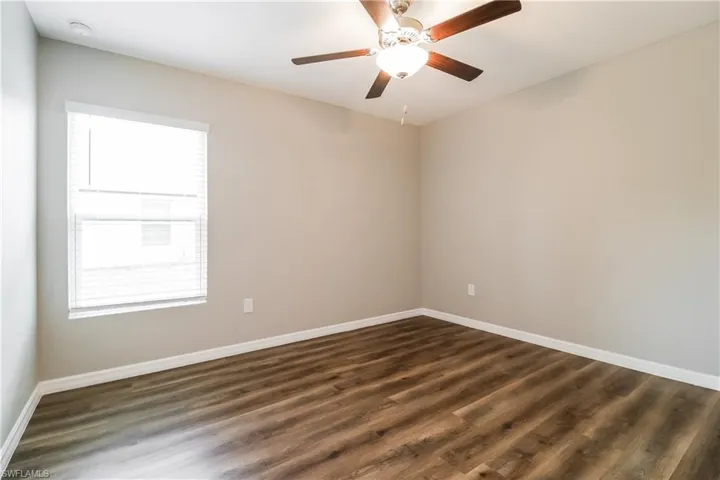 Spare room with dark wood-style flooring and a ceiling fan