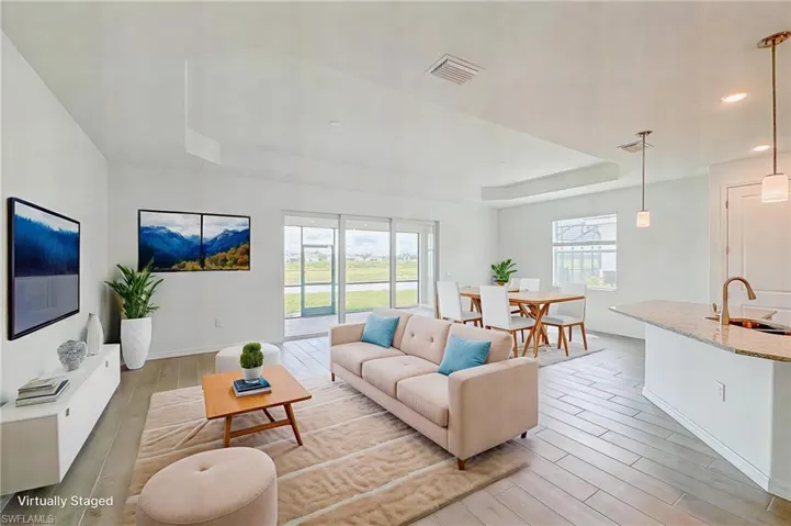 Living room featuring a raised ceiling, light wood finished floors, and recessed lighting