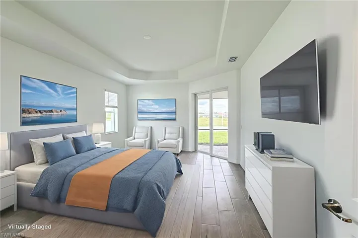 Bedroom featuring a raised ceiling, wood finished floors, multiple windows, and access to exterior