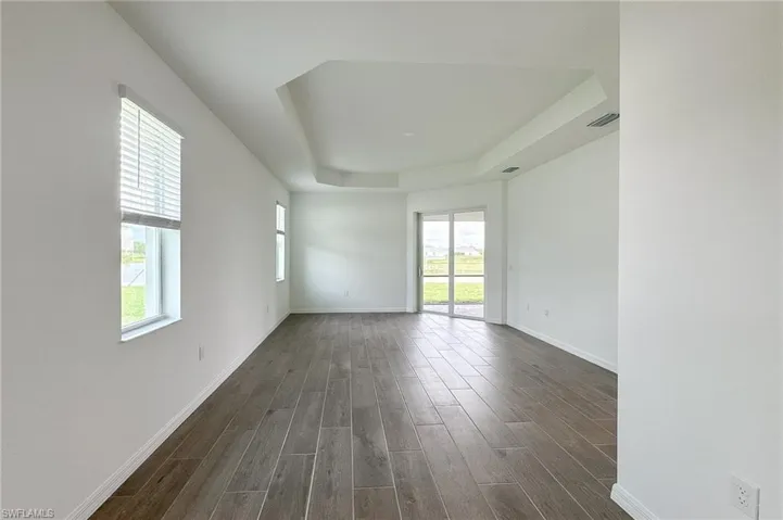 Spare room with a tray ceiling and dark wood-style floors