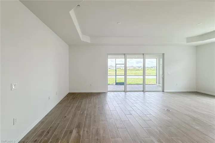 Empty room with a raised ceiling, wood finished floors, and a water view