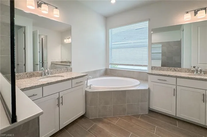Bathroom featuring two sinks, a garden tub, and vanity