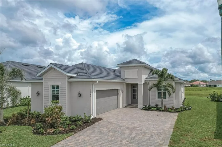 View of front of property featuring an attached garage, a front lawn, stucco siding, decorative driveway, and a tile roof