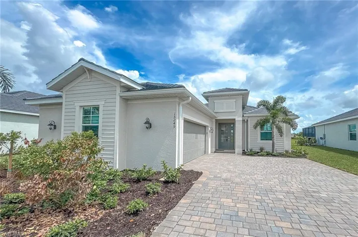 View of front of property featuring an attached garage, decorative driveway, and stucco siding