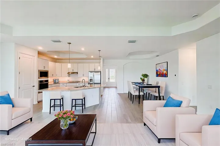 Living room with a raised ceiling, light wood finished floors, and recessed lighting