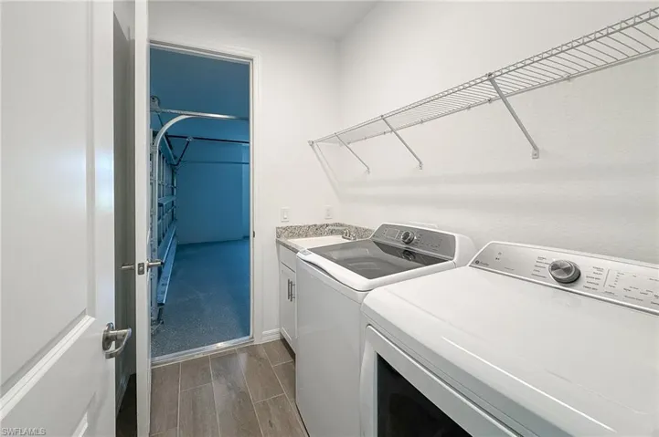 Washroom featuring wood finish floors, washer and clothes dryer, and cabinet space