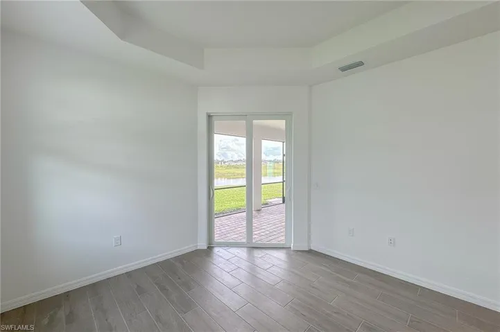 Empty room featuring a raised ceiling, a water view, and wood tiled floors