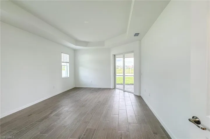 Spare room featuring a tray ceiling and wood tiled floors