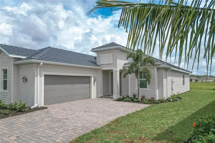 View of front of home featuring an attached garage, decorative driveway, and stucco siding