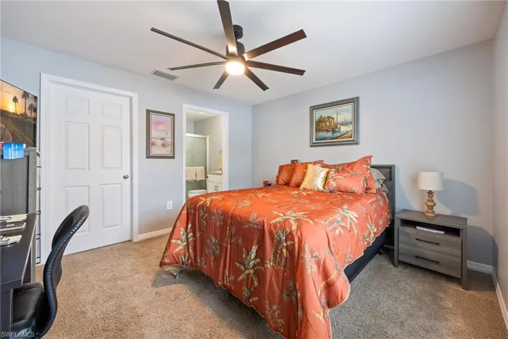 Bedroom with connected bathroom, carpet floors, and ceiling fan