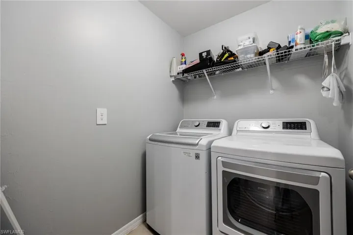 Laundry room with washer and clothes dryer and baseboards