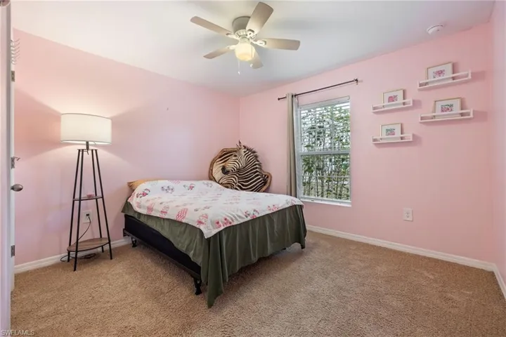 Carpeted bedroom with ceiling fan and baseboards
