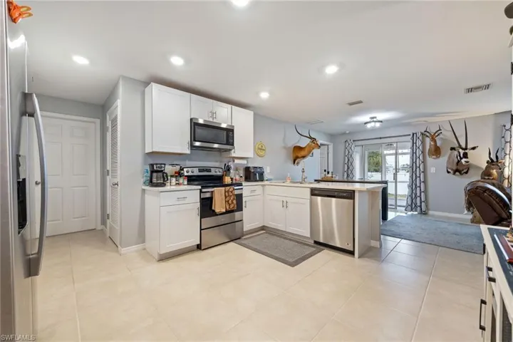 Kitchen with appliances with stainless steel finishes, white cabinetry, a peninsula, open floor plan, and light countertops