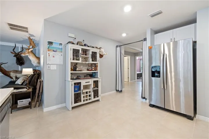 Kitchen with stainless steel appliances, white cabinets, light countertops, open shelves, and light tile patterned flooring