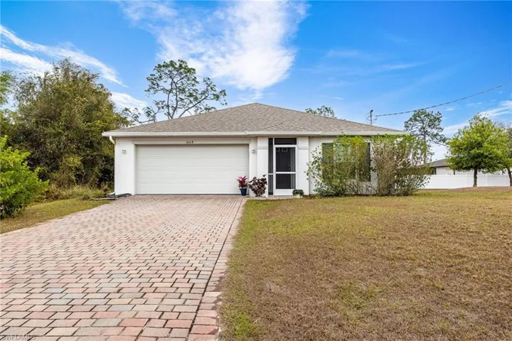 Ranch-style home with decorative driveway, stucco siding, a front yard, a garage, and a shingled roof