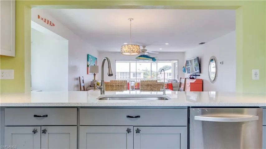 Kitchen featuring open floor plan, light stone counters, stainless steel dishwasher, hanging light fixtures, and recessed lighting