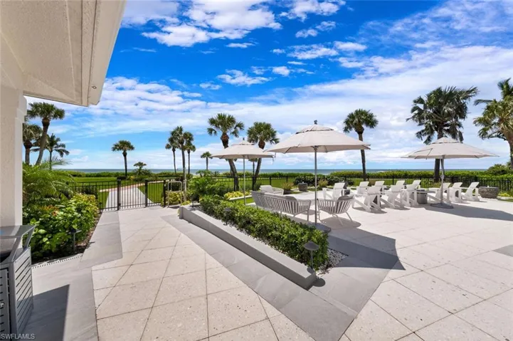 Steps to the Gulf/Beach! Pool area offers a wonderful niche seating area for all to enjoy day or night.  Left (under the captured roof as seen in this pic) is the covered open dining area with an Outdoor Kitchen & many Grills!