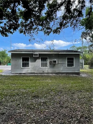 Rear view of house featuring a lawn and a wall mounted air conditioner