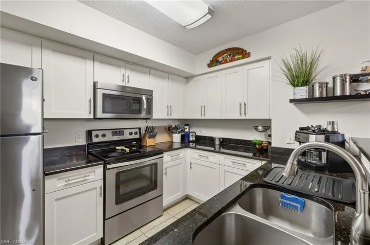 Kitchen featuring white cabinets, light tile floors, and appliances with stainless steel finishes