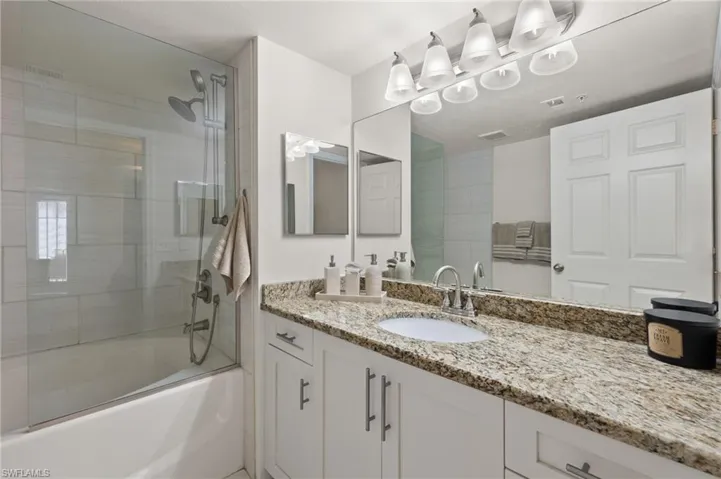 Bathroom featuring combined bath / shower with glass door and oversized vanity