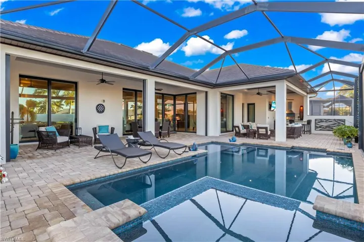 Heated pool and lanai with ambient lighting and panoramic water views, perfect for entertaining or relaxing.