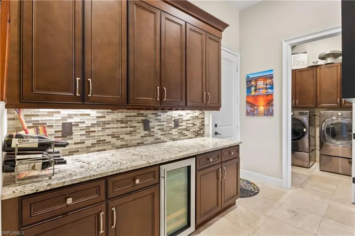 Open-concept kitchen with a double oven, wine cooler, breakfast bar, and natural light, perfect for hosting gatherings and sophisticated entertaining.