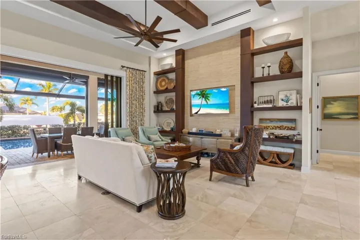 Elegant open-concept living room featuring travertine floors, natural light, and panoramic waterfront views.