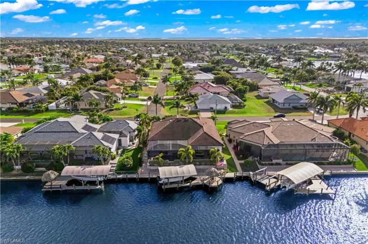 Bird’s-eye view capturing the canal, pool, and surrounding waterfront homes.