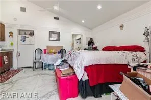 Bedroom with vaulted ceiling, freestanding refrigerator, recessed lighting, and ceiling fan